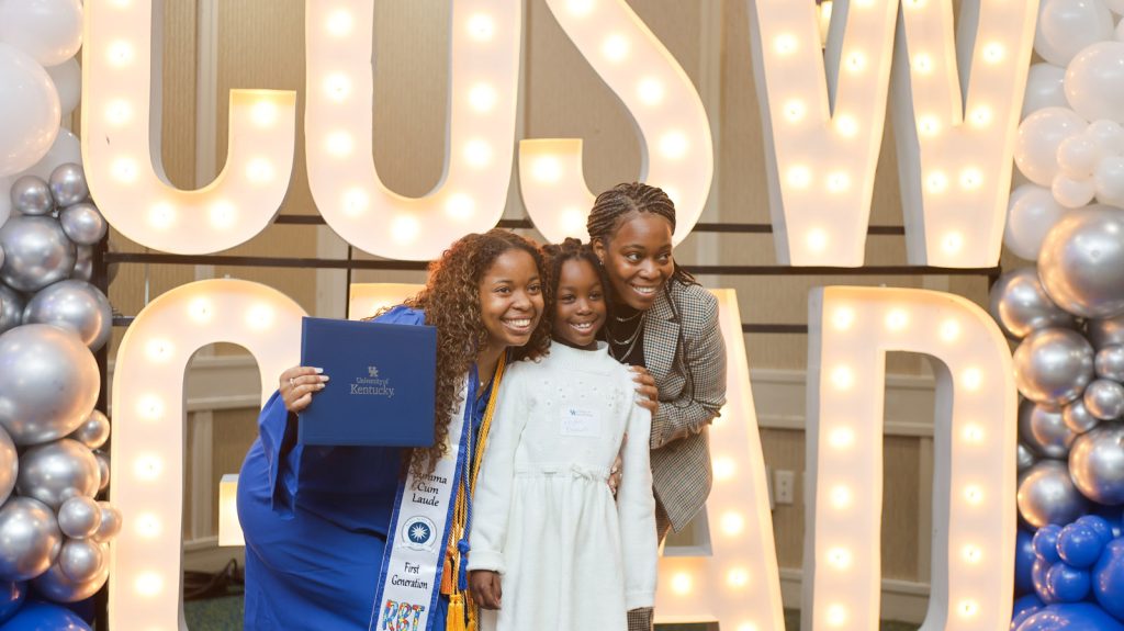 Family standing in front of a lighted CoSW Grad sign