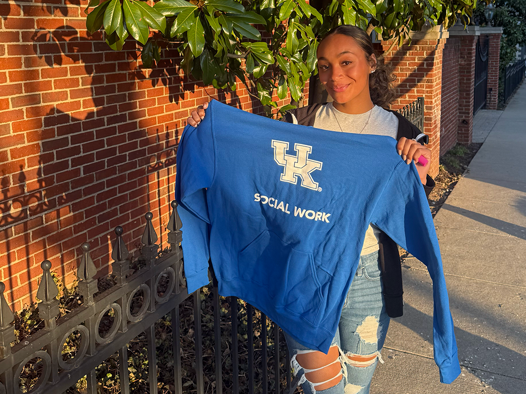MSW Student Serenity Burnett-Perry holding up a UK Social Work sweatshirt