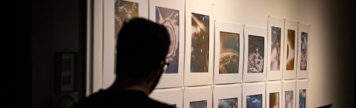 A man looking at photography hanging on a wall