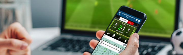 A person holding a phone while sports betting