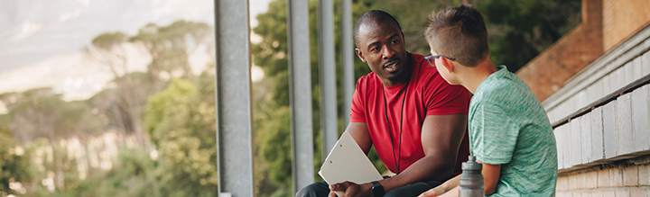 A coach talking to a young player in the bleachers